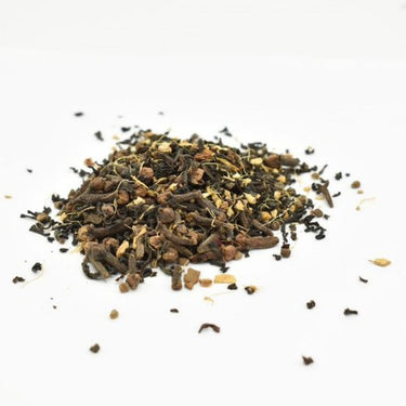 Masala Chai Loose Leaf Tea 🔥, featuring whole spices like cloves and cardamom, is scattered on a white background—ideal for brewing a rich, authentic chai latte.